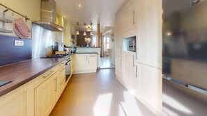 A modern kitchen with stainless steel appliances, wooden cabinets, and a long countertop.