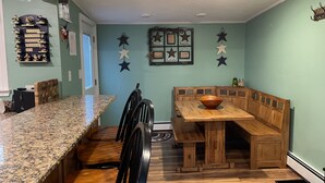 Une cuisine dotée d’un plan de travail en granit, de chaises en bois, d’un banc en bois et d’une table à manger en bois.