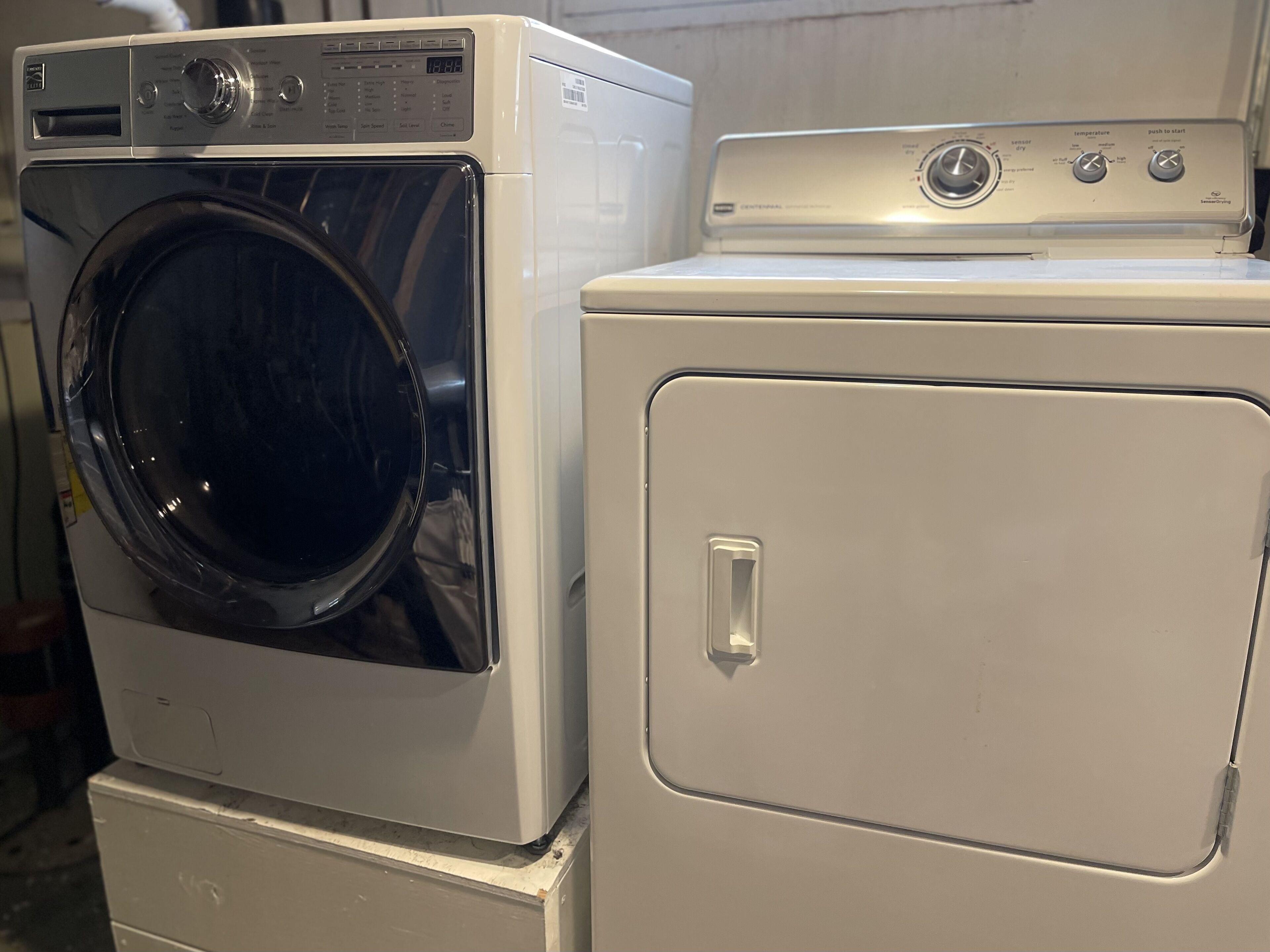 Een gestapelde wasmachine en droger met bedieningspaneel en een deurklink.
