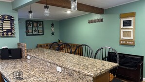 Une cuisine dotée d’un plan de travail en granit, de chaises en bois et de luminaires suspendus.