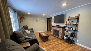 Un salon avec une cheminée, un canapé, une table basse et un téléviseur fixé au mur.