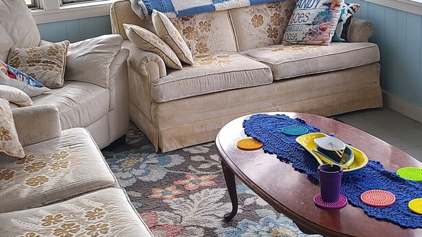 En stue med en beige sofa, et sofabord og et stort vindue.