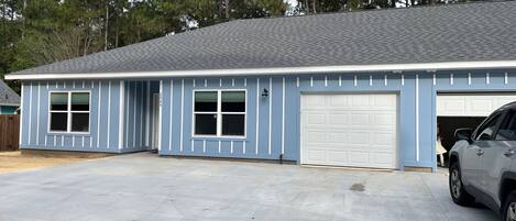 A single-story building with a garage, a driveway, and a vehicle parked in front.