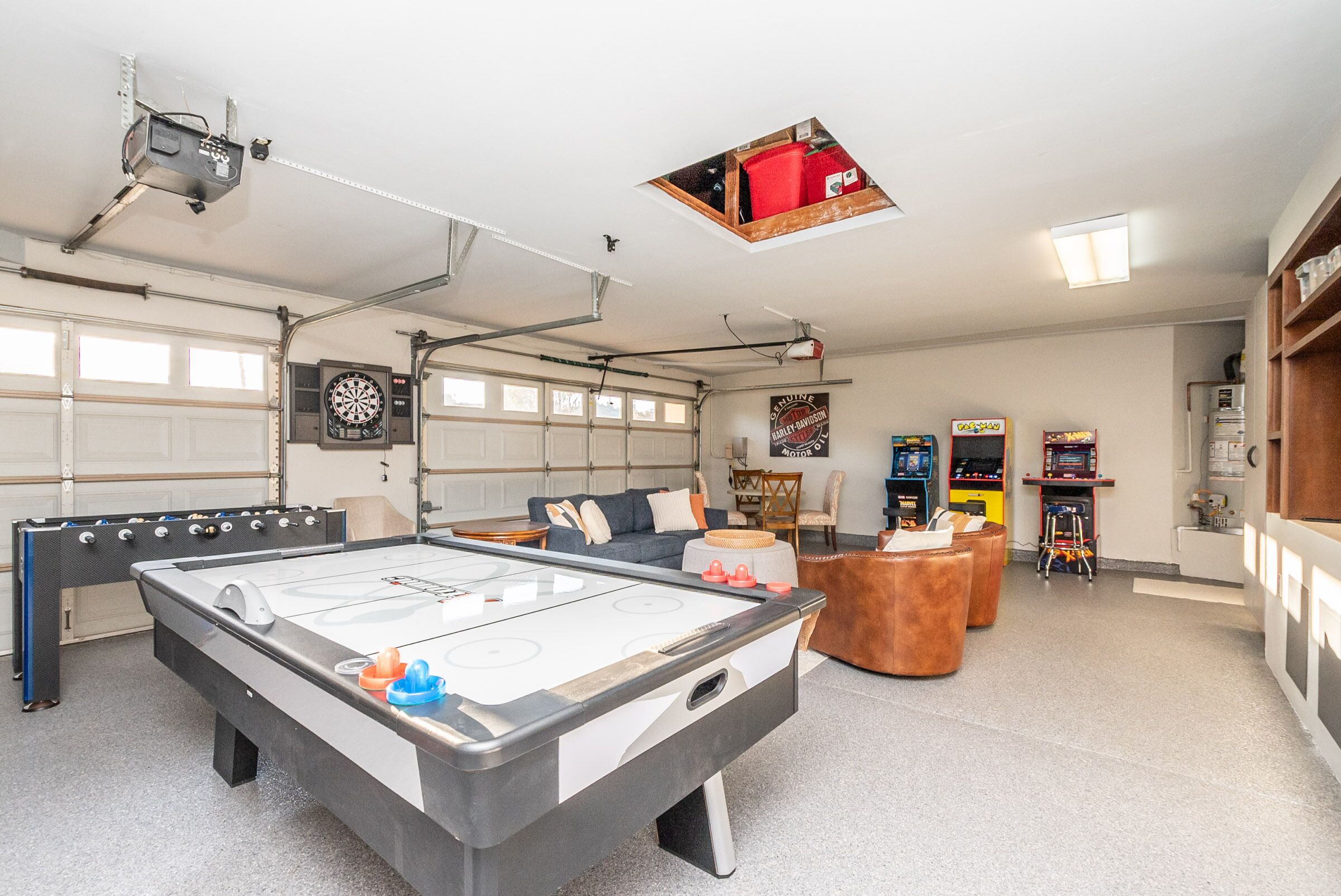 A recreational room with a foosball table, dartboard, and arcade games.