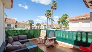 Une terrasse avec une piscine, du mobilier d’extérieur et une vue sur les palmiers et les maisons.