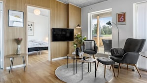 Una sala de estar moderna con una cama, un televisor y un balcón con jacuzzi.