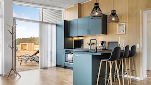 Una cocina moderna con una isla central, taburetes de bar y vistas al exterior.