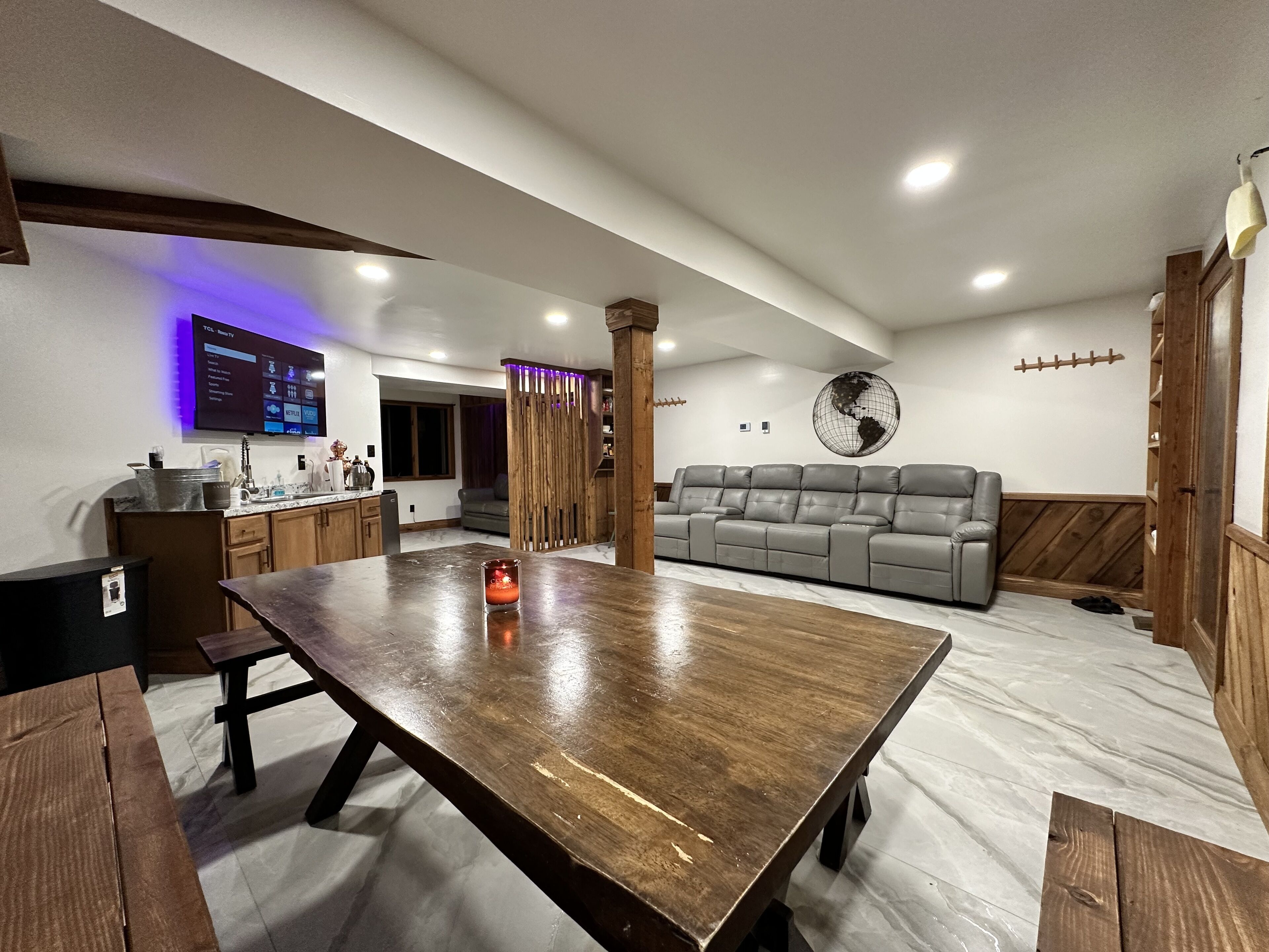 Un salón moderno con una mesa de comedor de madera, un sofá gris y un gran adorno de globo en la pared.