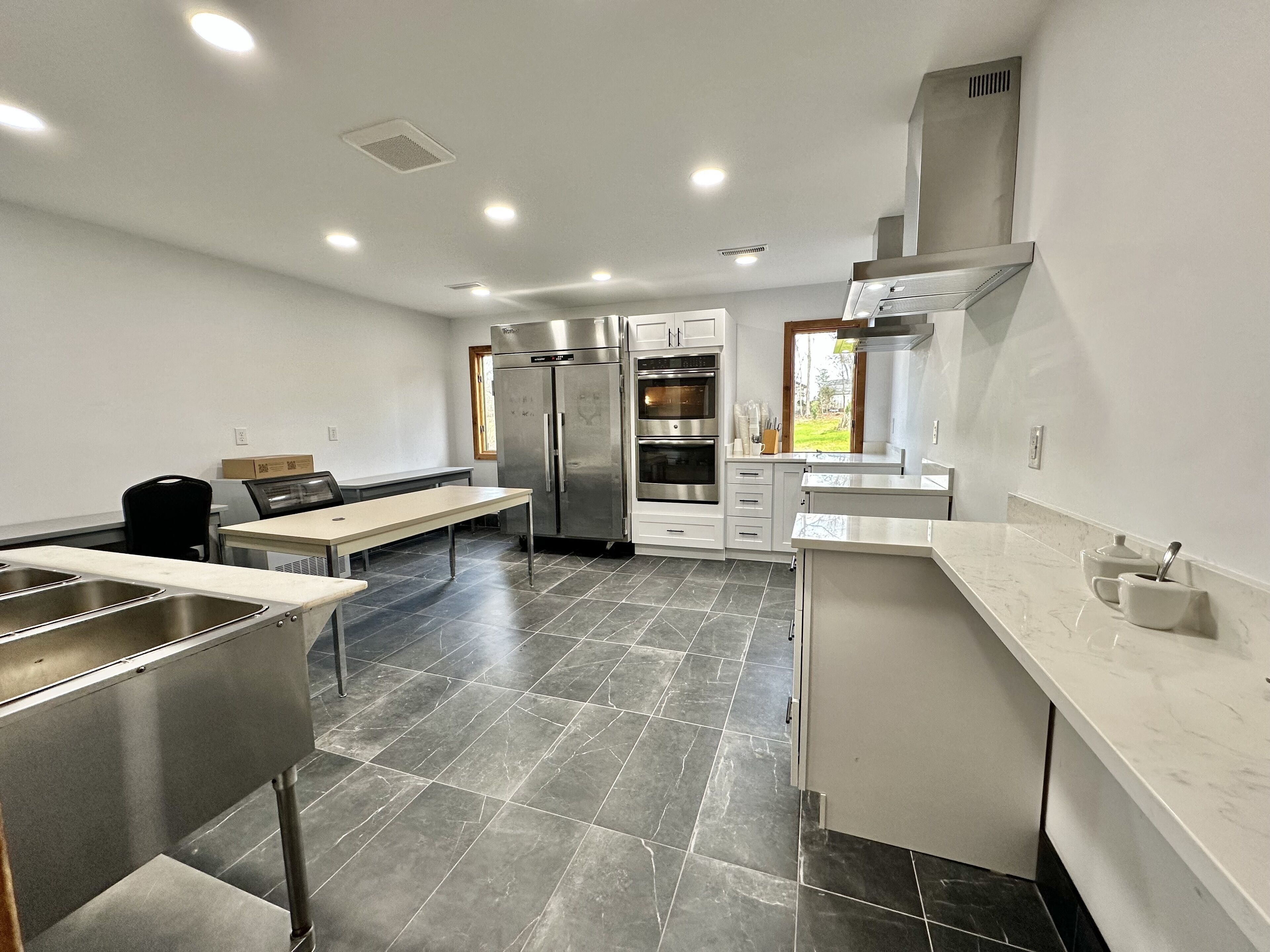 Een moderne keuken met roestvrijstalen apparatuur, een eetgedeelte met een bank en een groot raam met uitzicht op de omgeving.