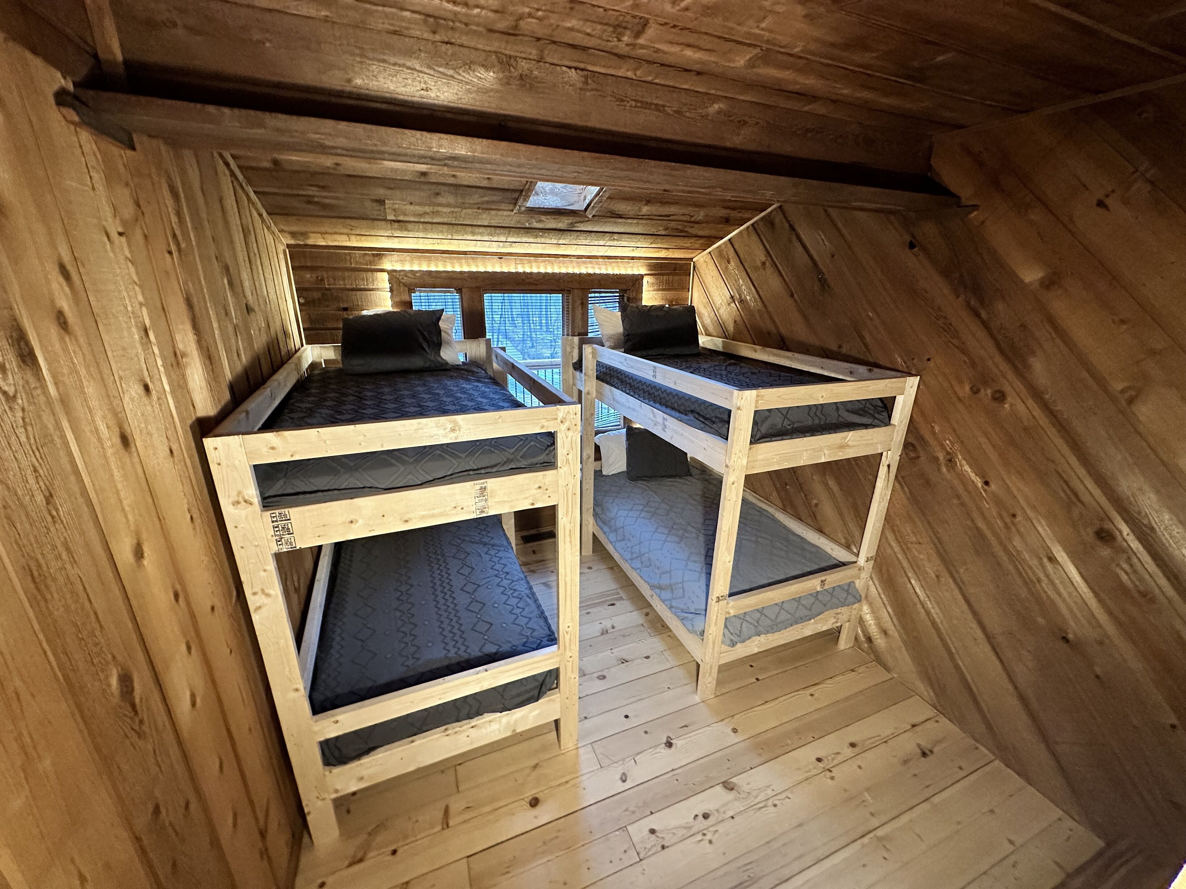 Un dormitorio con dos literas, paredes de madera y un tragaluz.