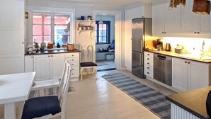 Eine moderne Küche mit weißen Schränken, einem Edelstahl-Kühlschrank und einem Essbereich mit weißem Tisch und Stühlen.