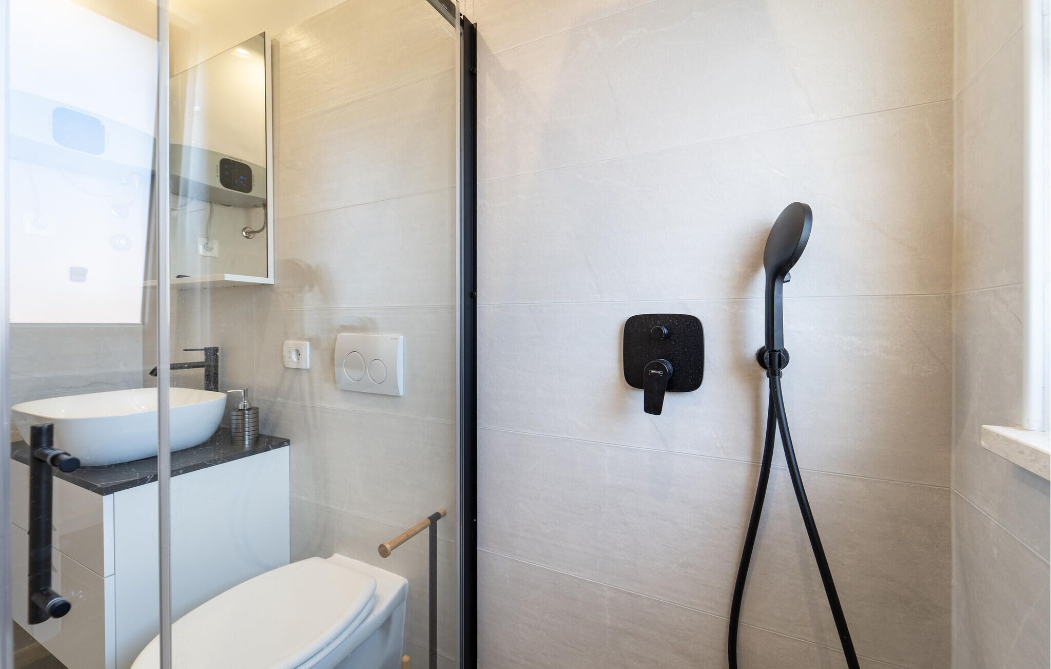 Une salle de bain moderne avec une douche à parois de verre, un lavabo blanc et des toilettes.