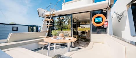 Le pont d’un yacht, avec un espace repas, une bouée de sauvetage et une échelle.