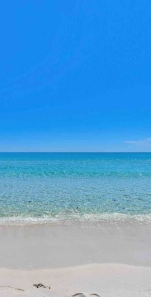 A beach with clear blue water and a sandy shore.