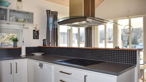 Une cuisine moderne avec un dosseret de carrelage noir, des meubles blancs et un lave-vaisselle encastré.