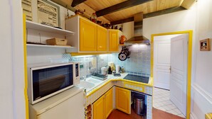 A compact kitchen with yellow cabinets, a microwave, and a tiled backsplash. - ⚓ L’Avant Port | Stunning View of Honfleur’s Outer Harbor | 65 m² | 4 Guest (Honfleur)