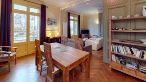 A spacious living room with a wooden dining table, comfortable seating, a bookshelf, and a television. - ⚓ L’Avant Port | Stunning View of Honfleur’s Outer Harbor | 65 m² | 4 Guest (Honfleur)
