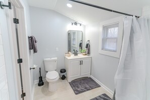 Un baño con inodoro, lavabo, espejo y cortina de ducha.