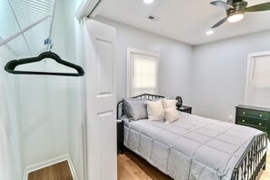Un dormitorio con cama, mesita de noche, cómoda y ventilador de techo.