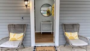 A front porch with two wicker chairs, a welcome mat, and a mirror on the wall. - Woodruff's Southern Nest, located few blocks from historic downtown Woodruff! (Woodruff)
