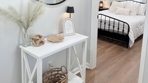 A white console table with a round mirror, a small lamp, and decorative items. - Woodruff's Southern Nest, located few blocks from historic downtown Woodruff! (Woodruff)
