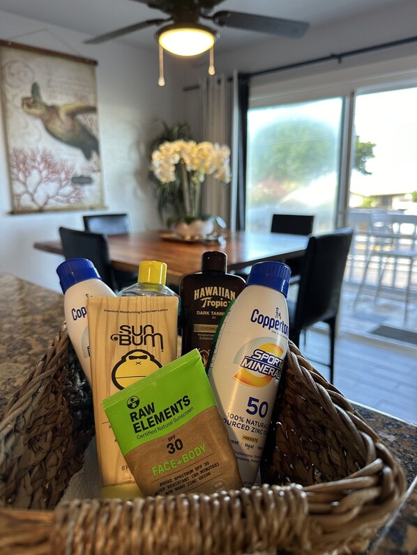A basket containing sunscreen bottles and a bottle of coconut oil on a kitchen counter.
