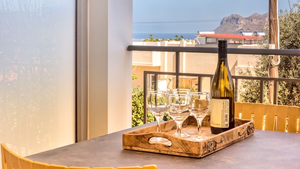 Ein Balkon mit Tisch, einer Weinflasche und Gläsern auf einem Tablett.