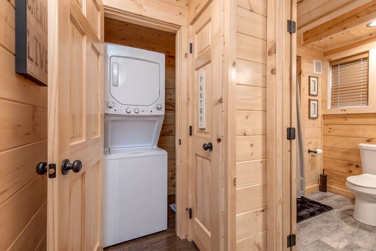 A wooden interior with a white washing machine and a toilet.