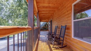 A wooden cabin with a porch, rocking chairs, and a view of the surrounding forest. - Fall & Winter Specials - Dog Friendly! LOCATION, LOCATION, LOCATION!! (Pigeon Forge)