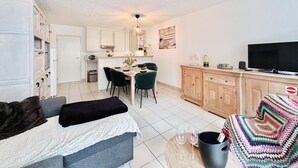 Un espace de vie compact comprenant une kitchenette, un coin repas et un téléviseur.