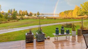 Une terrasse en bois agrémentée de jardinières, avec vue sur un lac et des arbres.