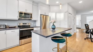 A modern kitchen with white cabinets, stainless steel appliances, and a central island with bar stools.