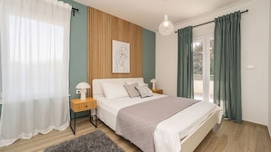 A bedroom with a bed, bedside tables, a hanging light fixture, and a window with curtains. - Stunning apartment in Bibinje (Bibinje)