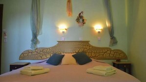 Quarto com uma cama grande, duas mesas de cabeceira e uma cabeceira com padrão rachado.