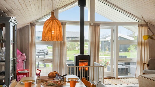 A cozy room with a large window, a fireplace, and a dining table set for a meal.