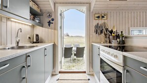 A compact kitchen with a large window, wooden cabinets, and a view of the outdoors.
