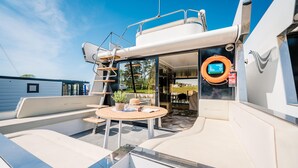 Däcket på en lyxyacht med ett matområde, en livboj och en stege.