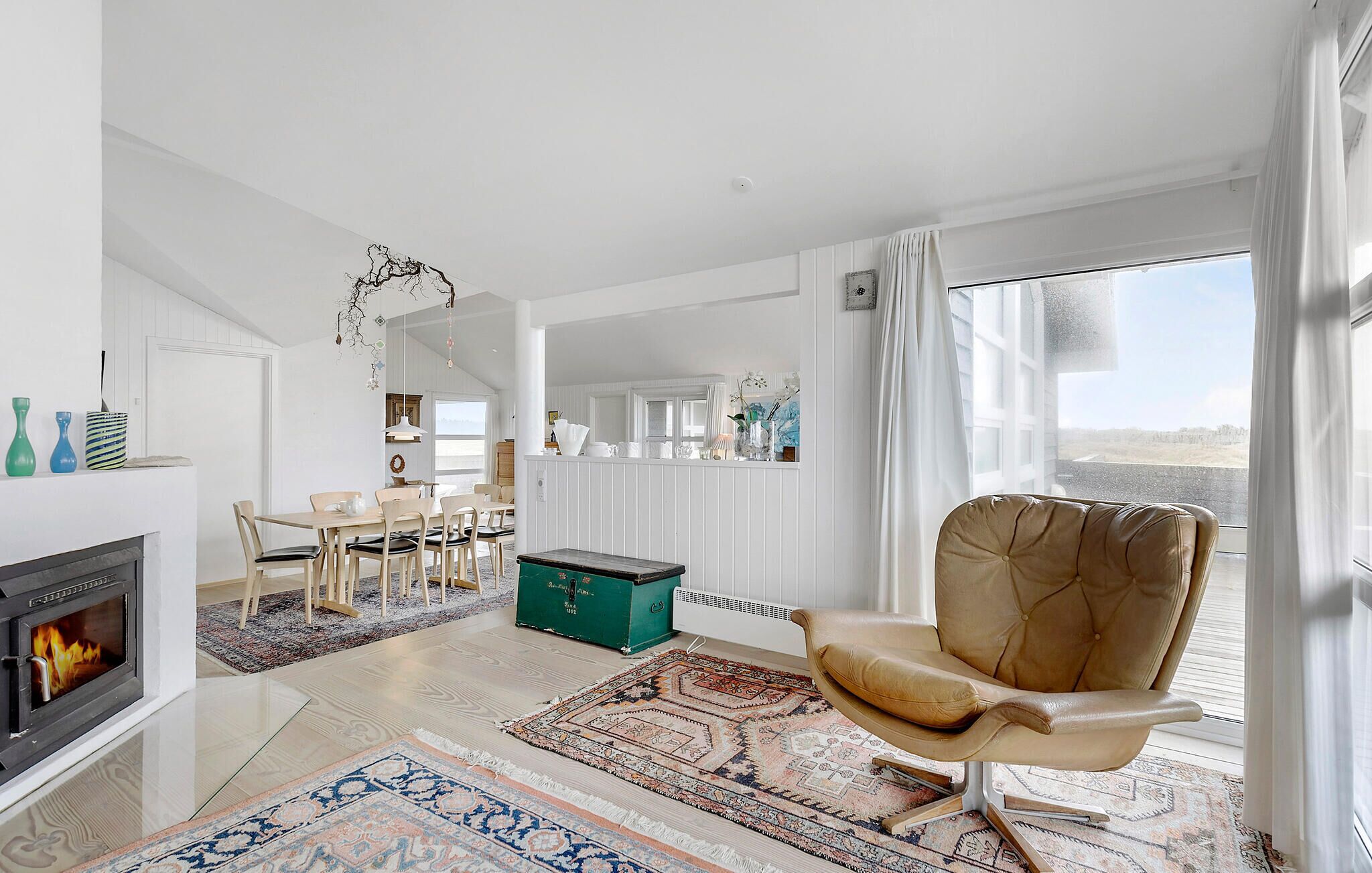A spacious living room with a fireplace, a dining area, and a view of the outdoors.