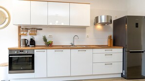 A modern kitchen with white cabinets, a stainless steel refrigerator, and a built-in oven. - Nice apartment in Bibinje (Bibinje)