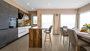Eine moderne Küche mit einer zentralen Kochinsel, Holzschränken und einem Essbereich mit Tisch und Stühlen.