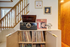 Una escalera con barandillas de madera, un tocadiscos y una colección de discos de vinilo en estanterías.
