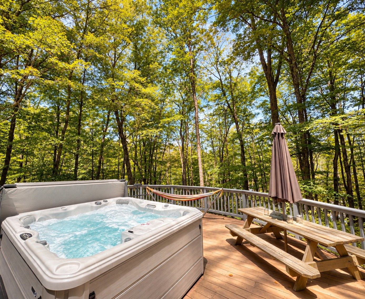 A hot tub on a wooden deck surrounded by trees.