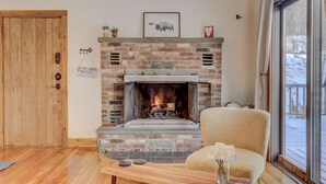 Una sala de estar acogedora con chimenea de ladrillo, una puerta de madera y vistas al exterior.
