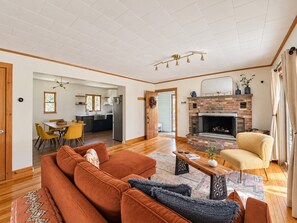 A living room with a fireplace, a dining area, and a kitchen. - Entire Catskills Retreat - Hot Tub • Sauna • Fireplace • Vinyl (Jeffersonville)