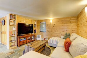 A cozy living room with a television, wooden shelves, a sofa, and a map on the wall. - Catskills Memories · Hot Tub· Sauna· Firepit· Vinyl (Jeffersonville)