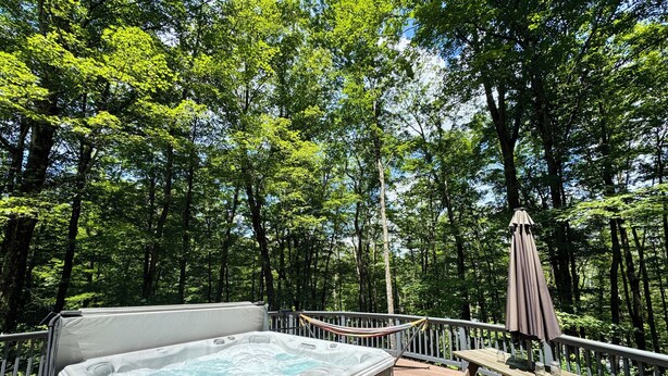 Un jacuzzi en una terraza de madera rodeado de un bosque.