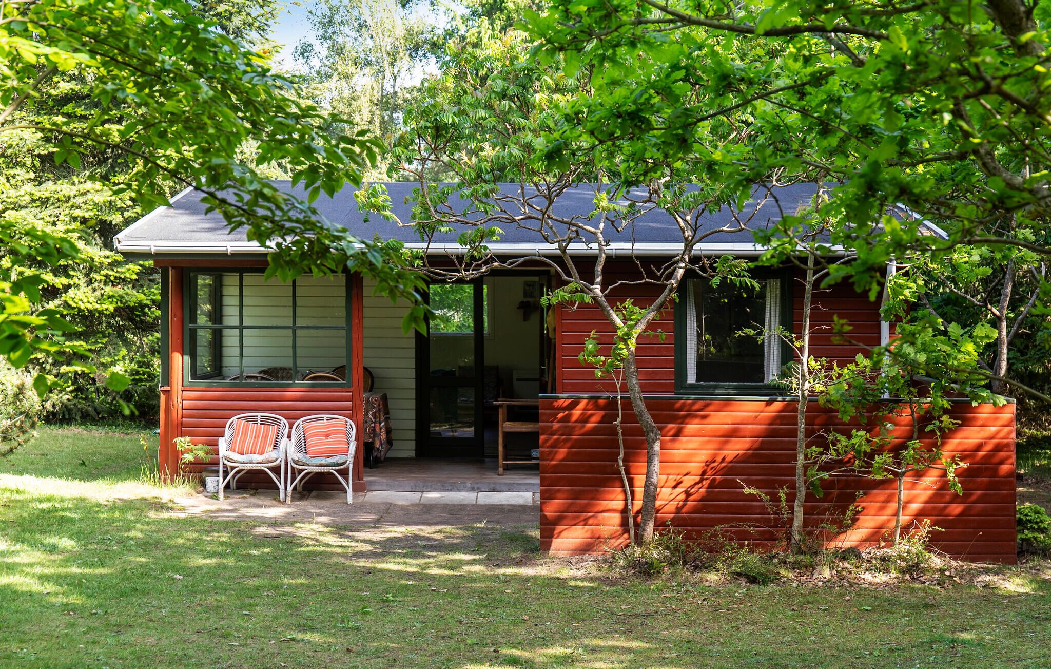A small, single-story house with a porch, a small table, and two chairs.