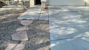 Une maison à deux étages avec un garage, une véranda et une allée gravillonnée.