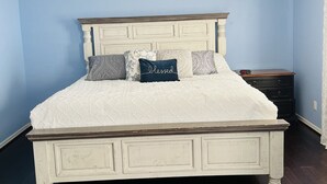 Une chambre à coucher avec un lit blanc, un ventilateur de plafond et une table de chevet.