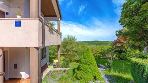 A hotel with a balcony, a garden with various plants and flowers, and a view of a hilly landscape. - 2 bedroom awesome apartment in Pazin (Pazin)